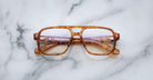 The Jacques Marie Mage Evans eyeglasses feature thick, oversized brown tortoiseshell rectangular acetate frames and are shown on a white marble surface.