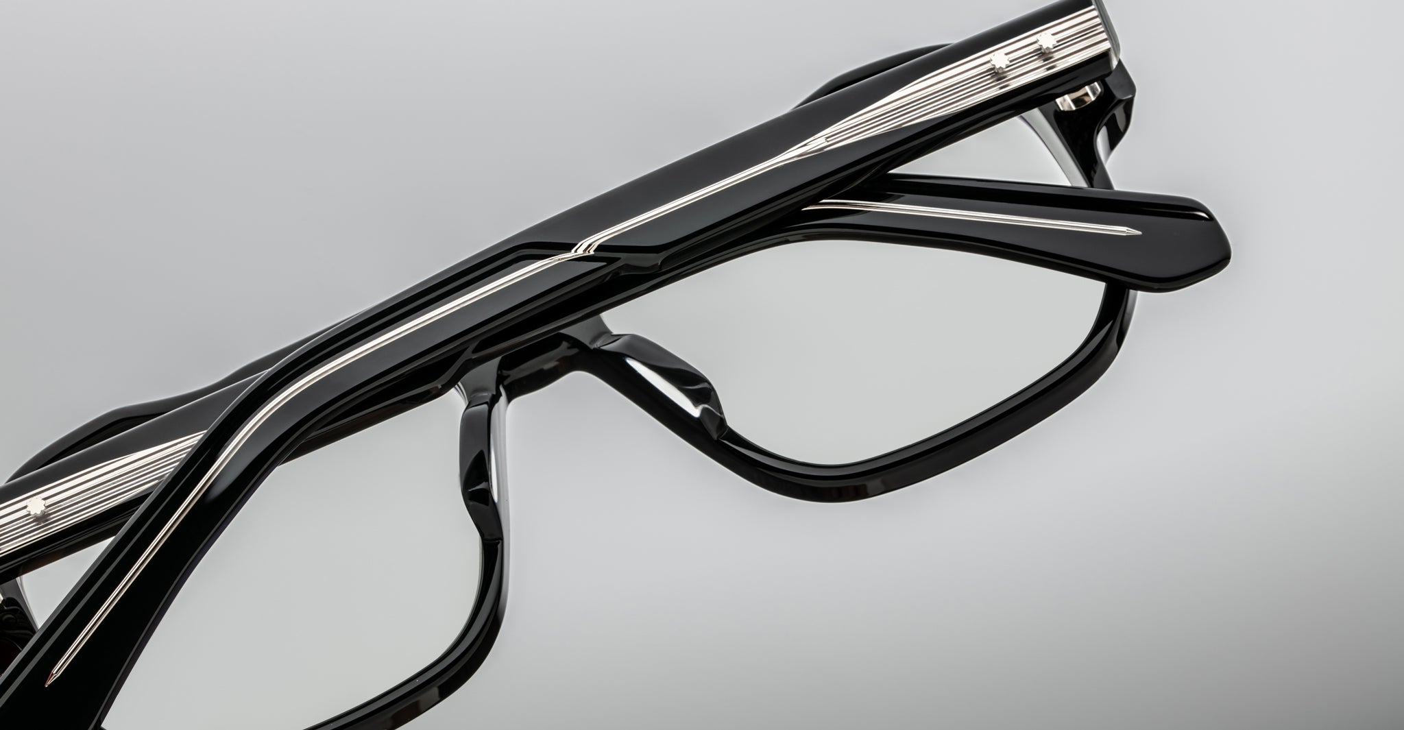 Close-up of Jacques Marie Mage Evans handcrafted optical glasses featuring silver detailing and an oversized acetate frame, displayed against a plain gray background.