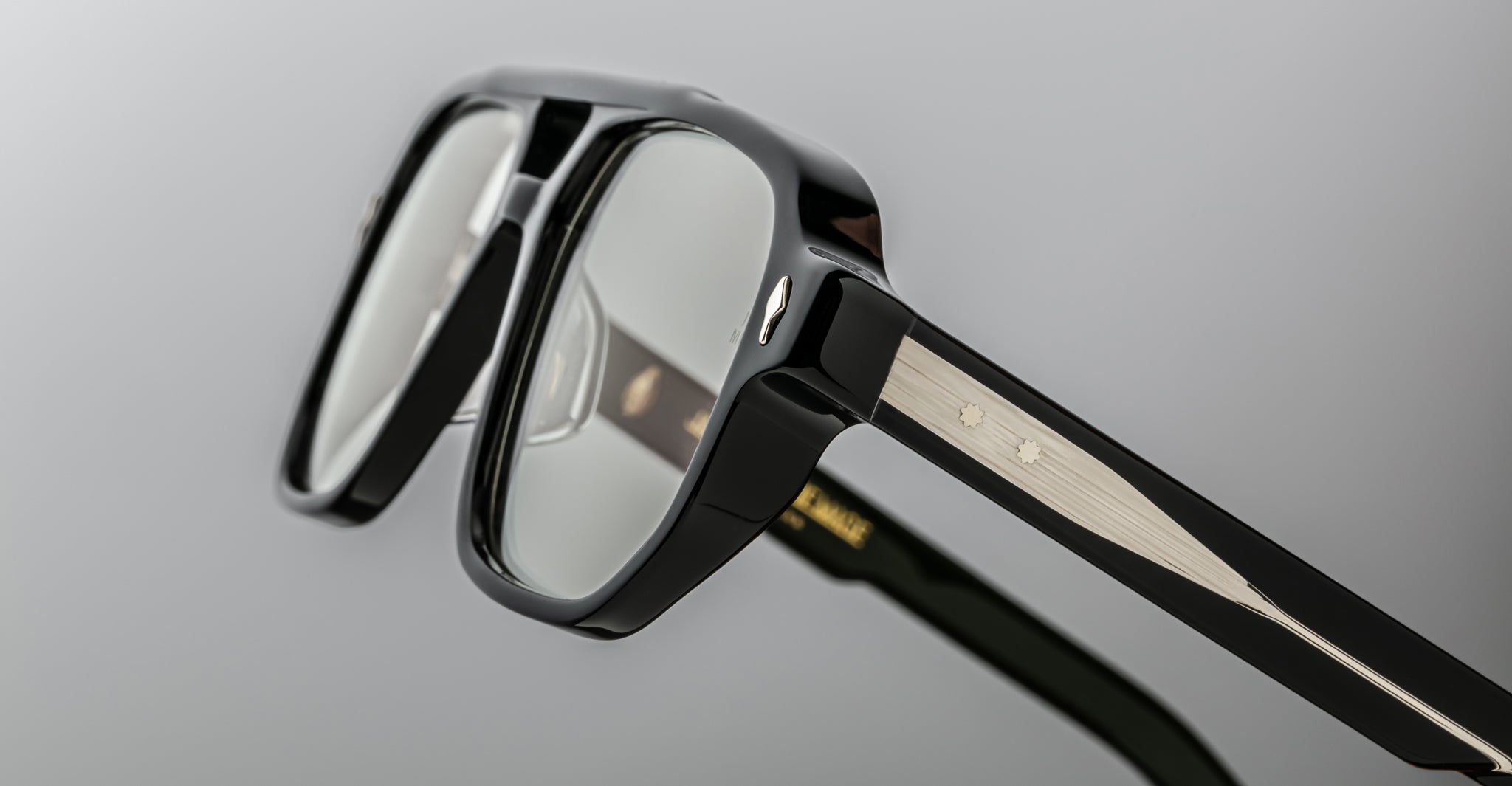Close-up of Jacques Marie Mage Evans optical glasses, featuring a black and silver oversized acetate frame with clear lenses and detailed temple hinges, set against a neutral background.