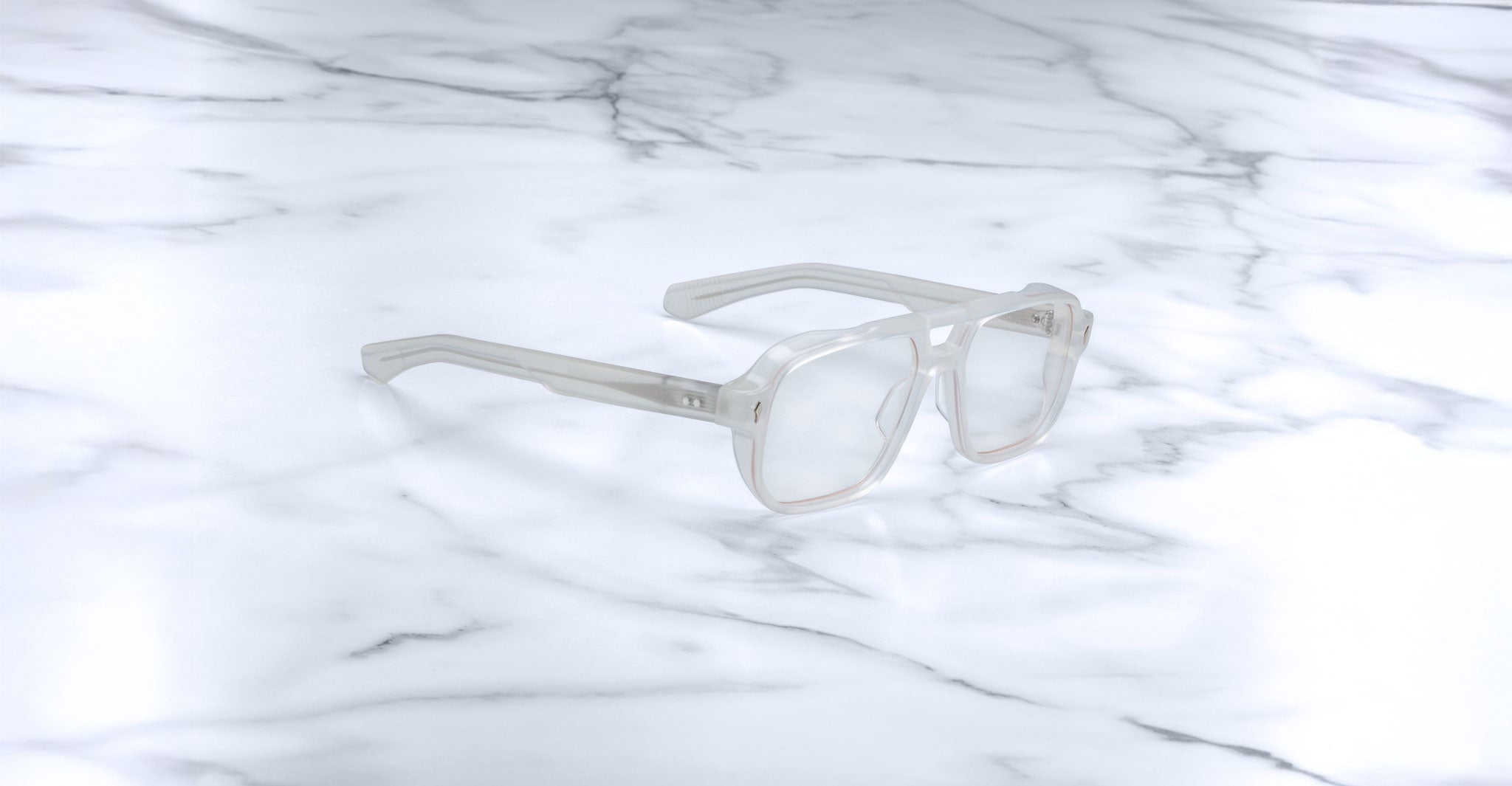 Jacques Marie Mage Evans: Oversized clear rectangular acetate eyeglasses by Jacques Marie Mage, handcrafted and displayed on a white marble surface.