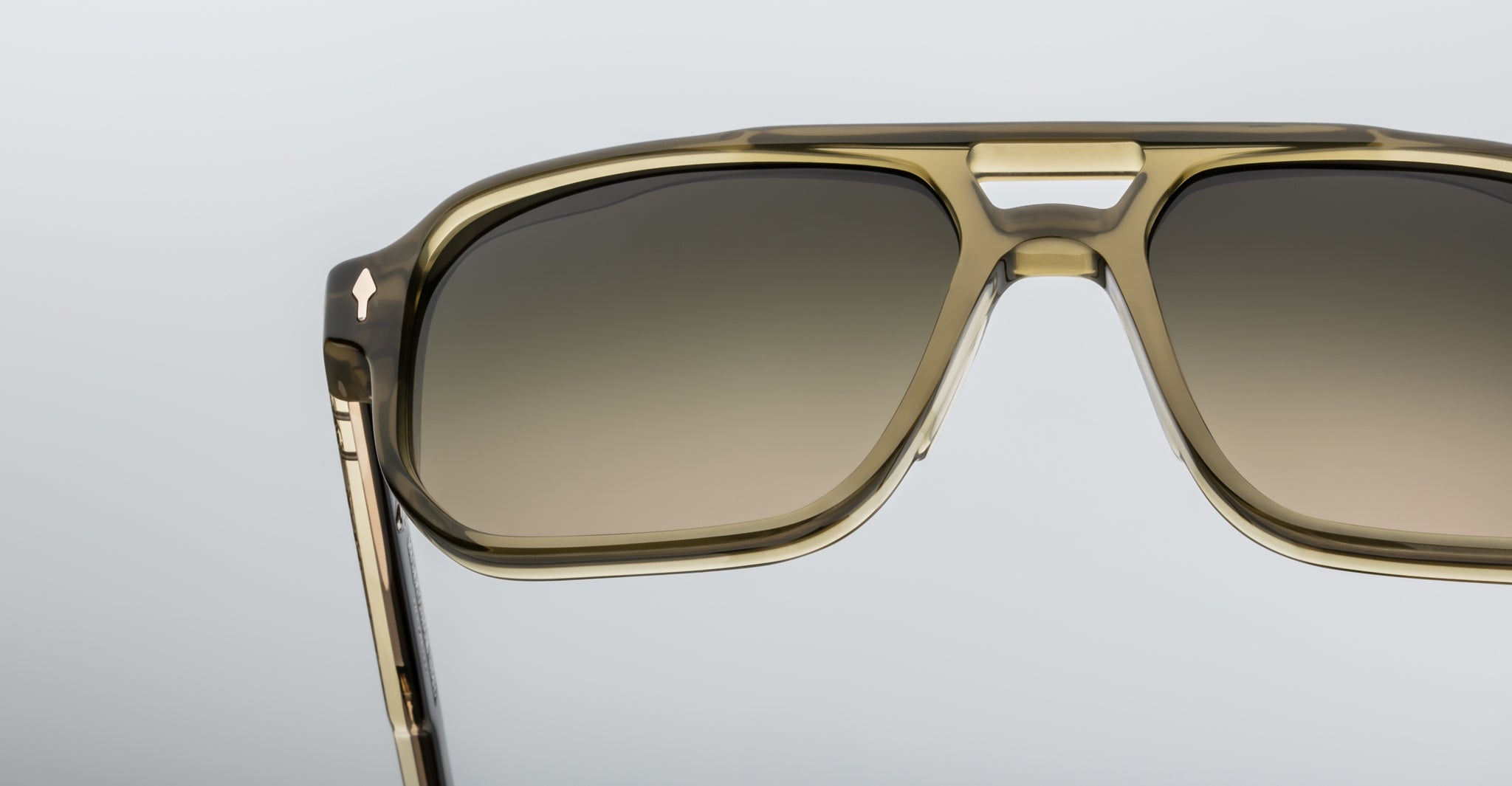 Close-up of Jacques Marie Mage Evans sunglasses featuring an oversized acetate frame in translucent khaki with brown gradient lenses, set against a plain light background.