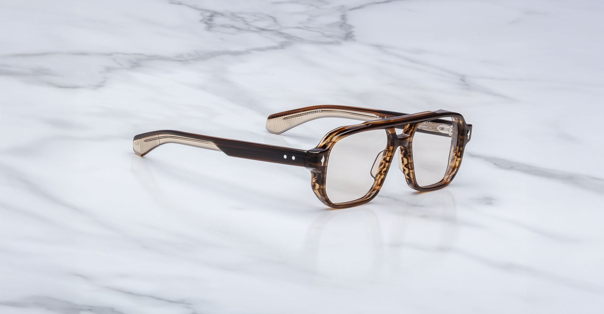 A pair of Jacques Marie Mage Evans brown tortoiseshell rectangular eyeglasses with clear lenses and an oversized acetate frame rests on a white marble surface.