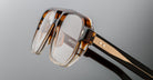 Close-up of Jacques Marie Mage Evans eyeglasses in brown tortoiseshell, featuring clear lenses, an oversized acetate frame with textured detail, and a small metallic accent on the temple.