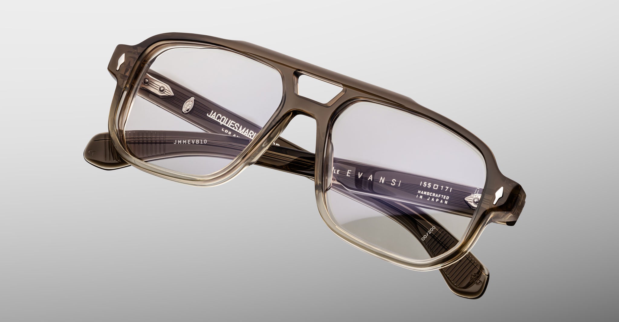 A pair of Jacques Marie Mage Evans eyeglasses featuring an oversized rectangular translucent brown acetate frame with clear lenses, shown on a light gray background.