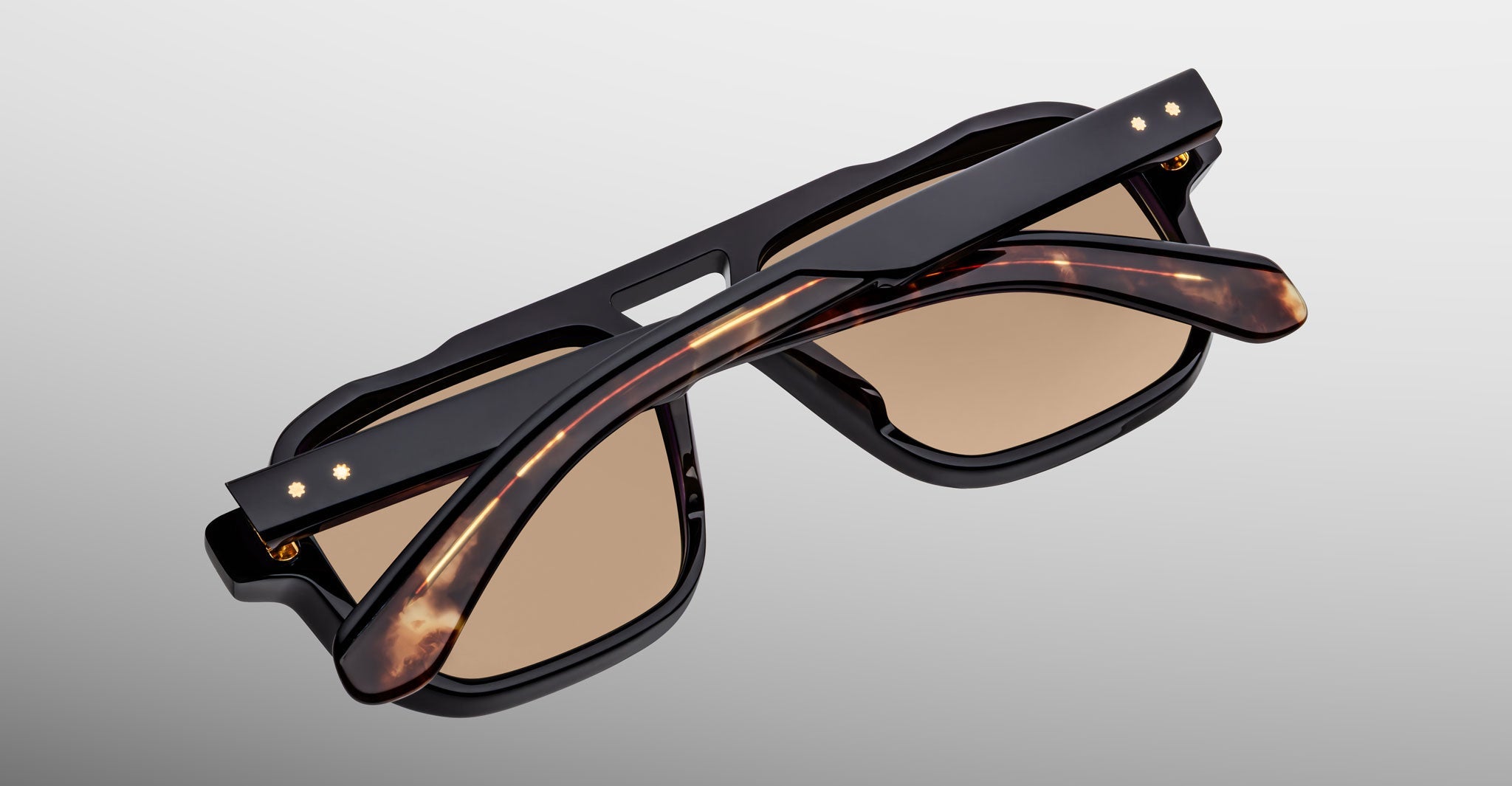The Jacques Marie Mage Evans sunglasses feature an oversized rectangular acetate frame with brown-tinted lenses and thick dark tortoiseshell arms, shown folded from above against a plain background.