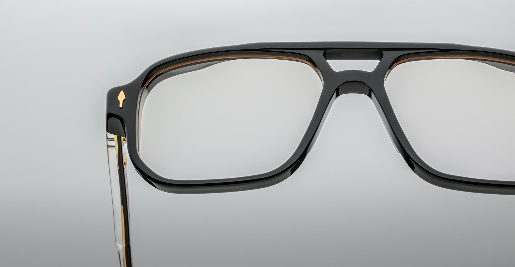 Close-up of the Jacques Marie Mage Evans black rectangular eyeglass frames, featuring a metal detail on the temple and oversized acetate design, shown against a plain light background.