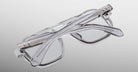 The Jacques Marie Mage Evans, a pair of handcrafted rectangular optical glasses by Jacques Marie Mage, is folded and set on a light gray gradient background.