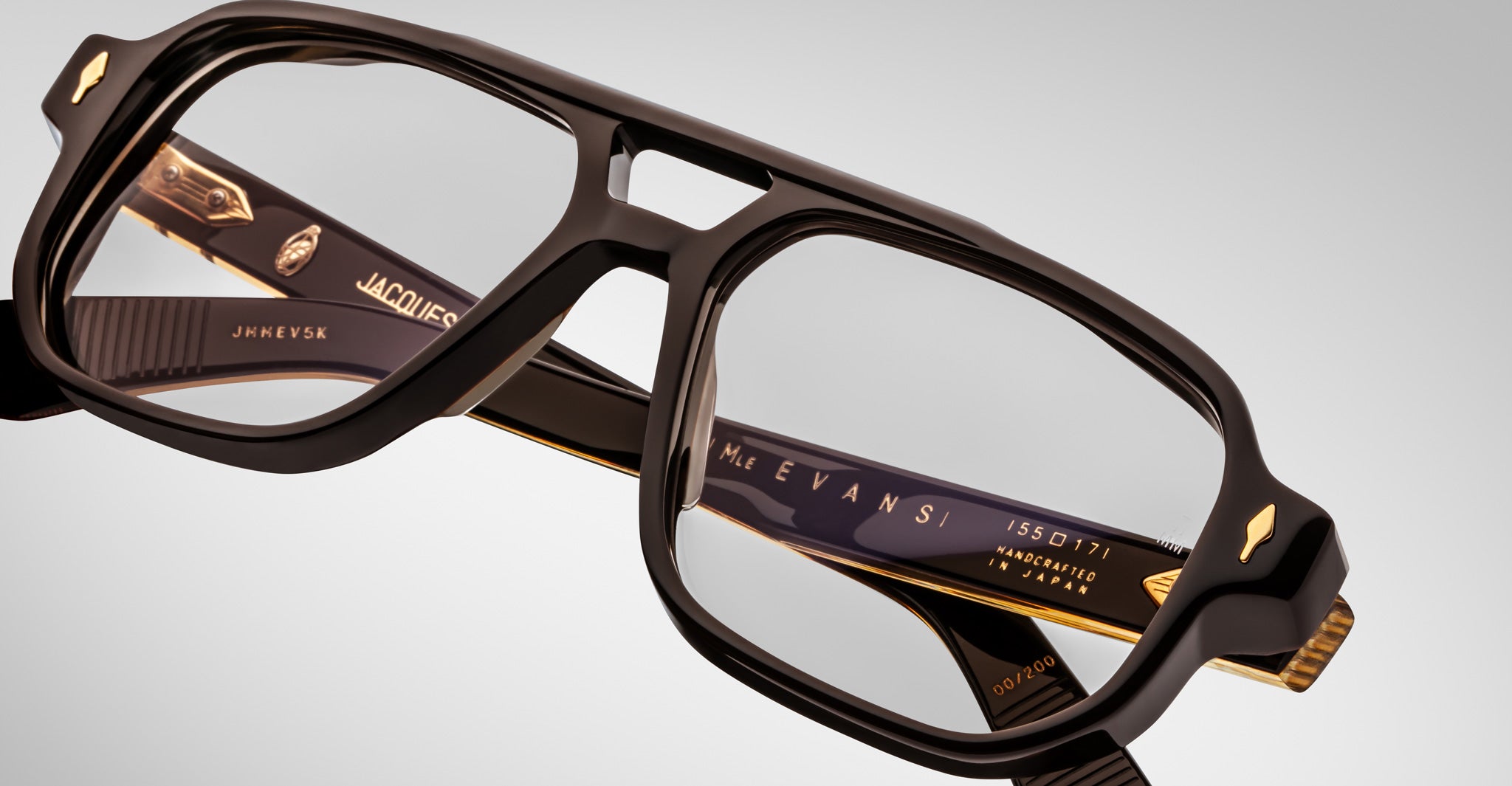 Close-up of Jacques Marie Mage Evans optical glasses, handcrafted with a black and gold oversized acetate frame featuring intricate design details and embossed inner arm text.