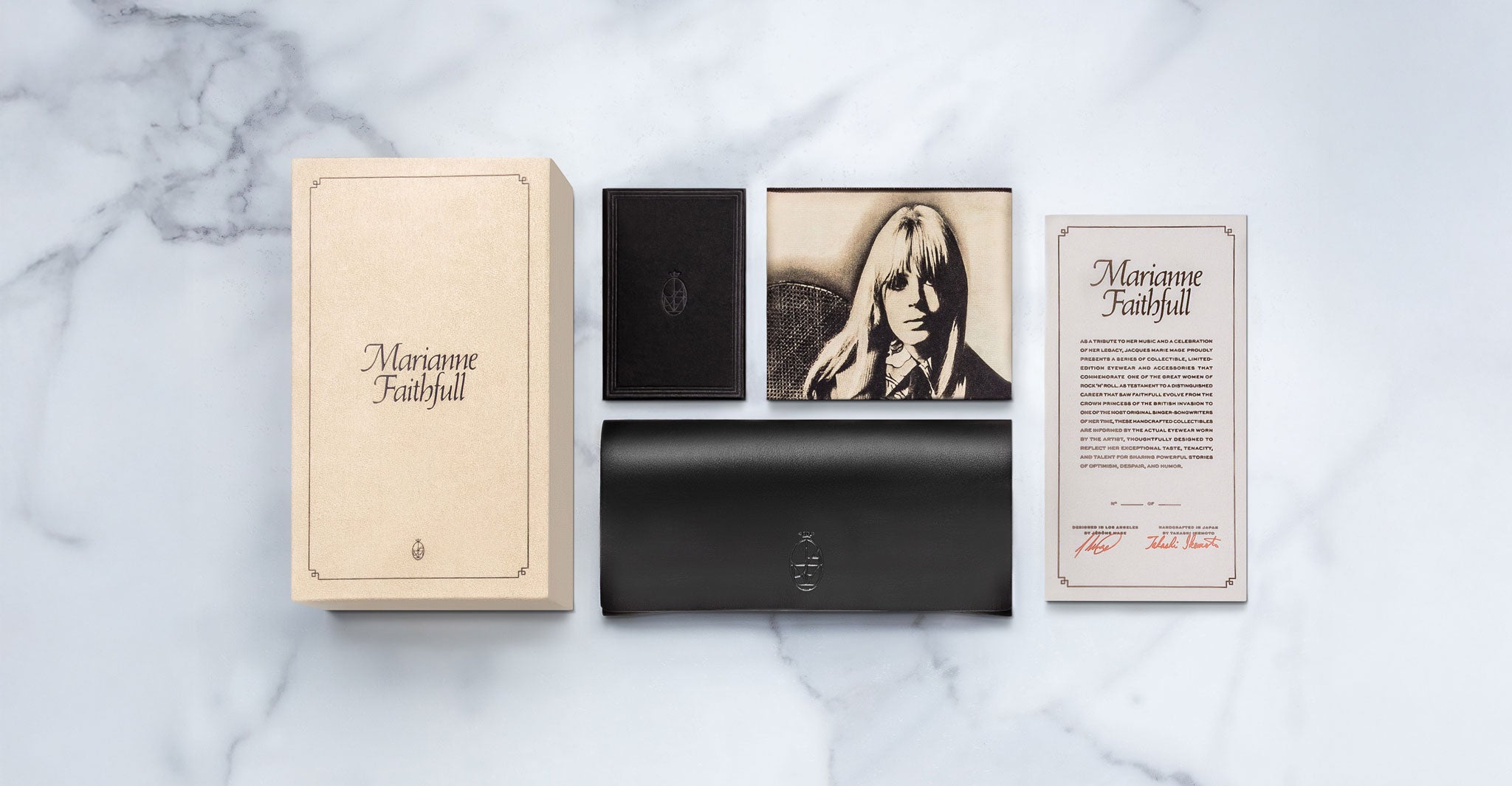 A beige box labeled “Jacques Marie Mage Evelyn,” a small black box, a black case, a booklet with a vintage-style portrait, and an informational card are arranged on a white marble surface.