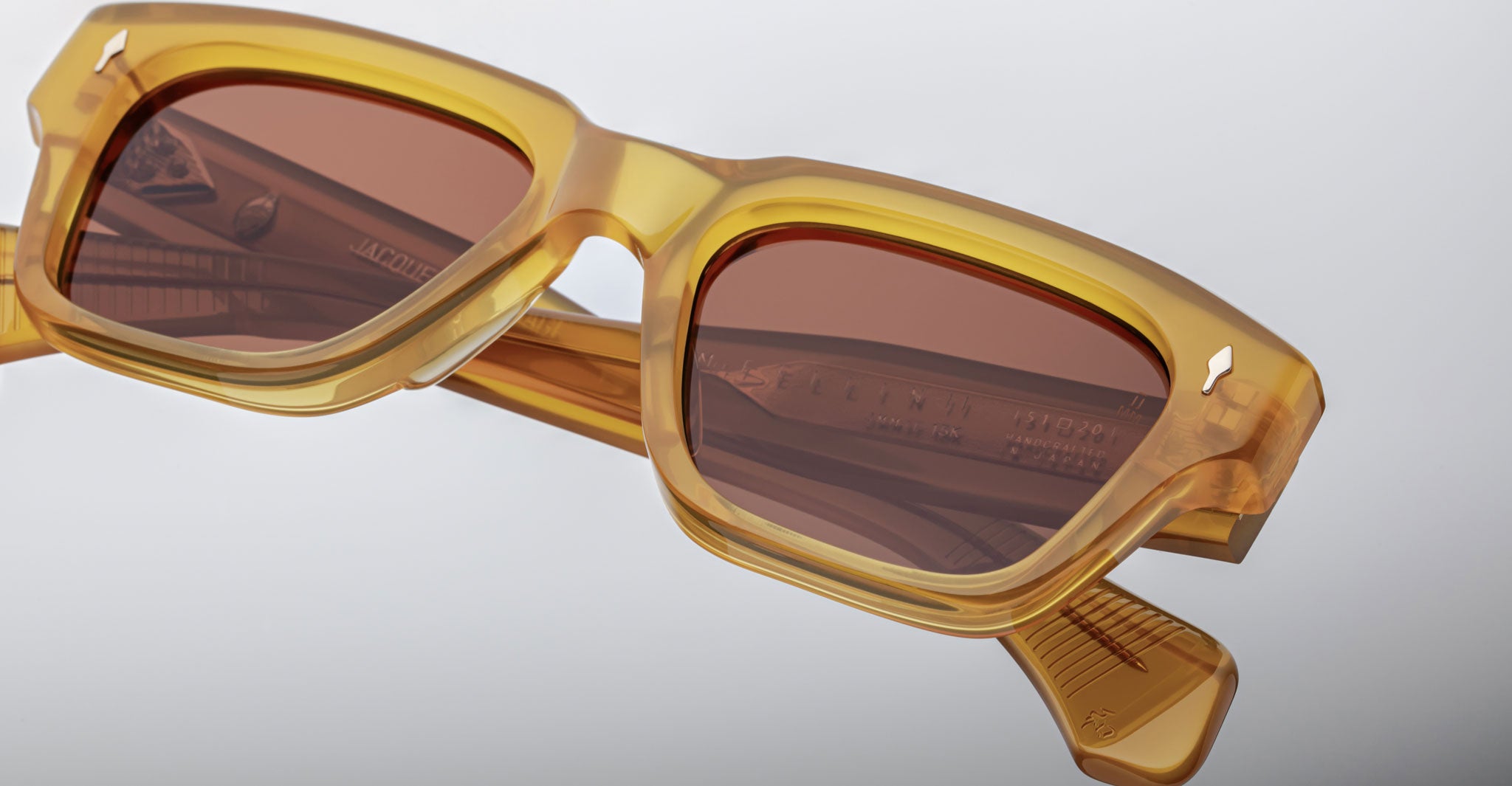 Close-up of Jacques Marie Mage Fellini rectangular sunglasses in translucent amber with brown lenses, stacked view.