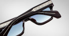 Close-up of Jacques Marie Mage Fellini sunglasses showing blue-tinted lenses, mirrored silver accents, and black frames.