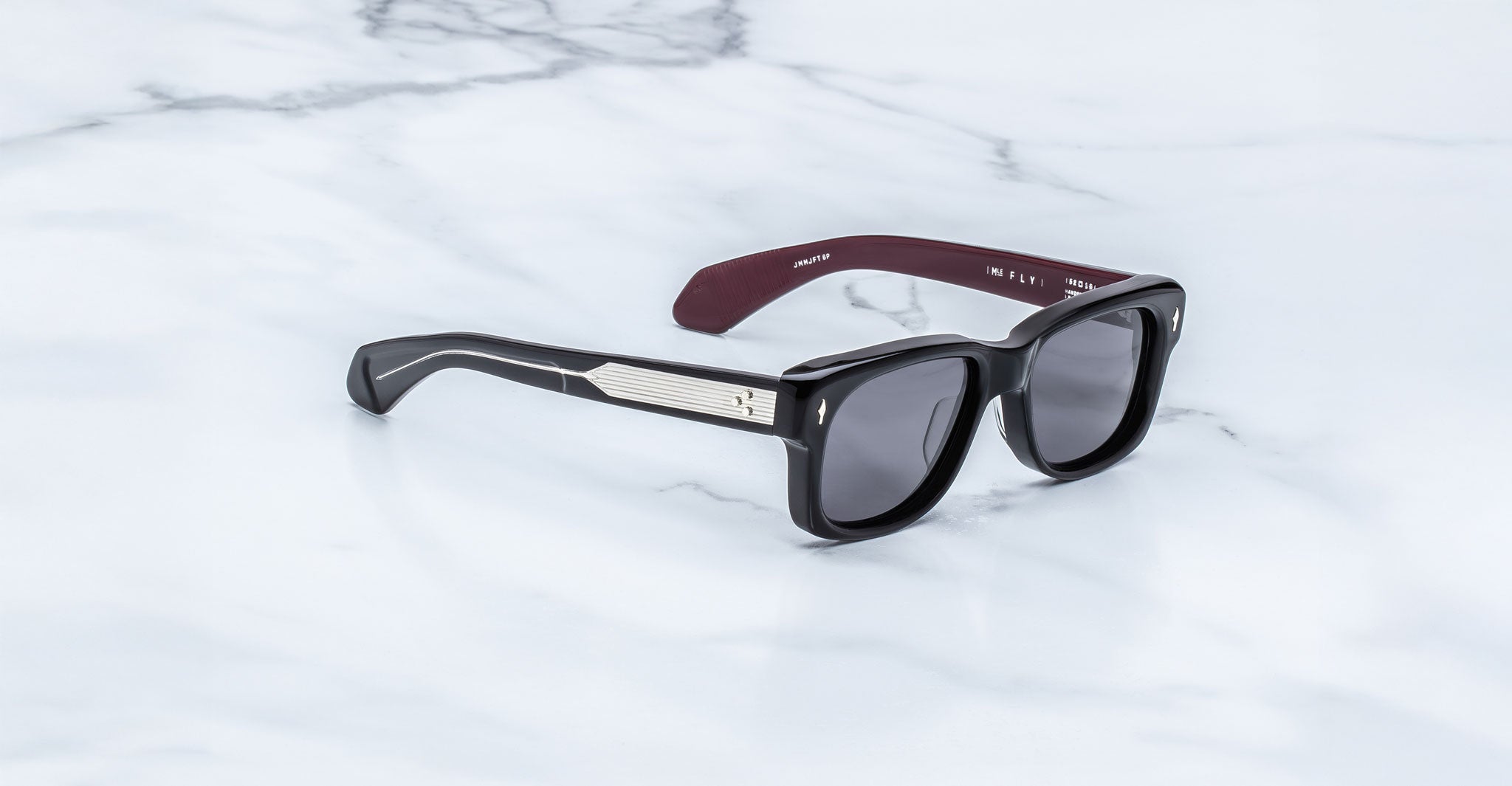Jacques Marie Mage Fly black rectangular sunglasses with metallic arms, shown from above.