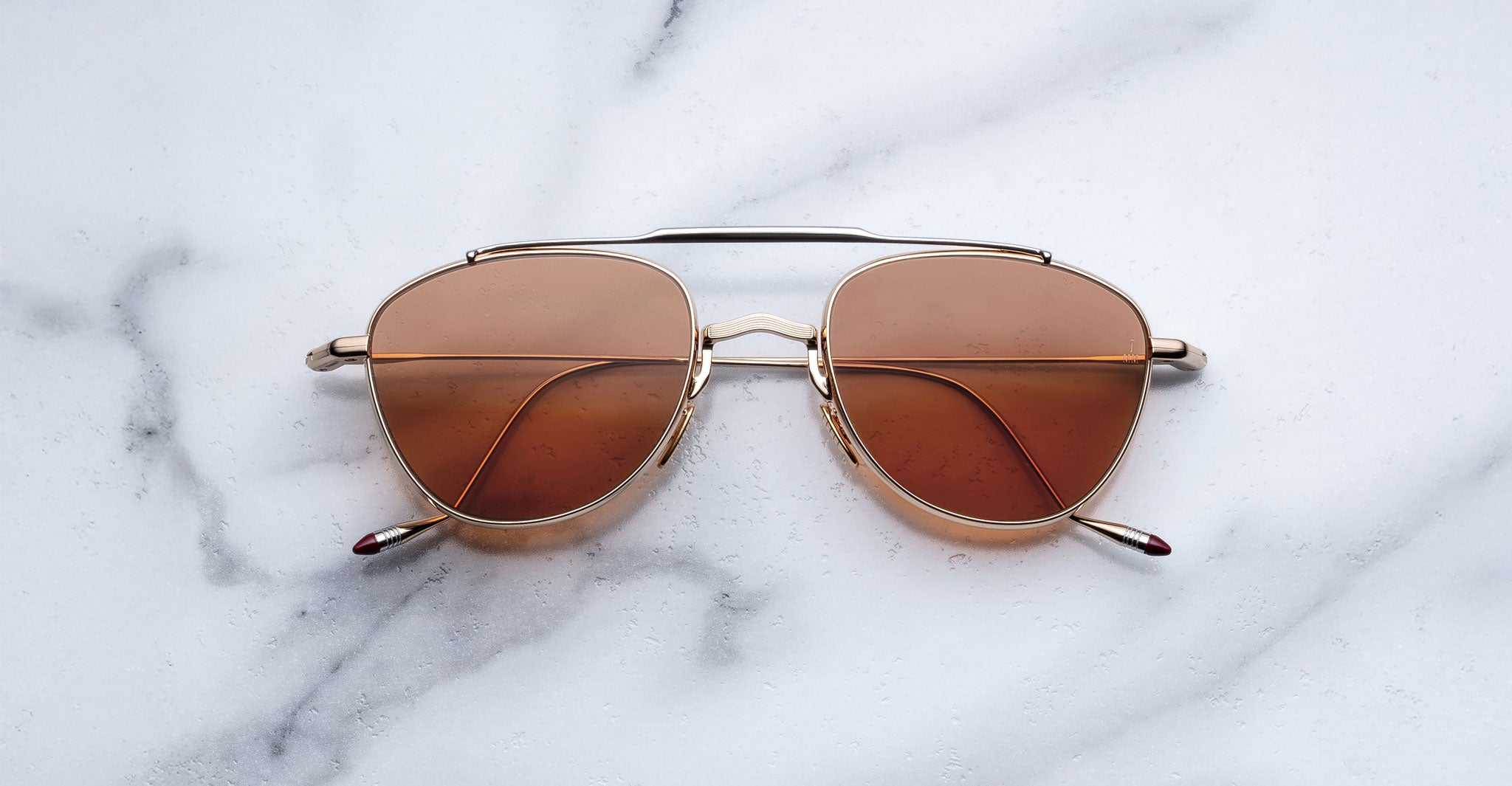 Jacques Marie Mage Flynn aviator sunglasses, top view, placed on white marble surface.