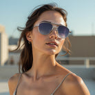 Model wearing Jacques Marie Mage Flynn sunglasses in silver with a relaxed outdoor setting.