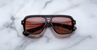 Jacques Marie Mage Fugue sunglasses with red-tinted lenses, top view, featuring bold frames on a white surface.