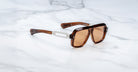 Jacques Marie Mage Fugue sunglasses, brown rectangular frame with UV-protection amber lenses and silver accents, front angle view.