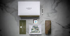 A flat lay of Jacques Marie Mage Full Metal Jacket merchandise on marble features a white box, metal screwdriver, camo glasses case, green envelope, keychain with blue drop, and a graphic card displaying the movie title.