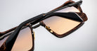 Close-up of Jacques Marie Mage GT-R sunglasses featuring rectangular gradient brown lenses, tortoiseshell frames, black arms, and gold lens accents displayed against a plain light background.
