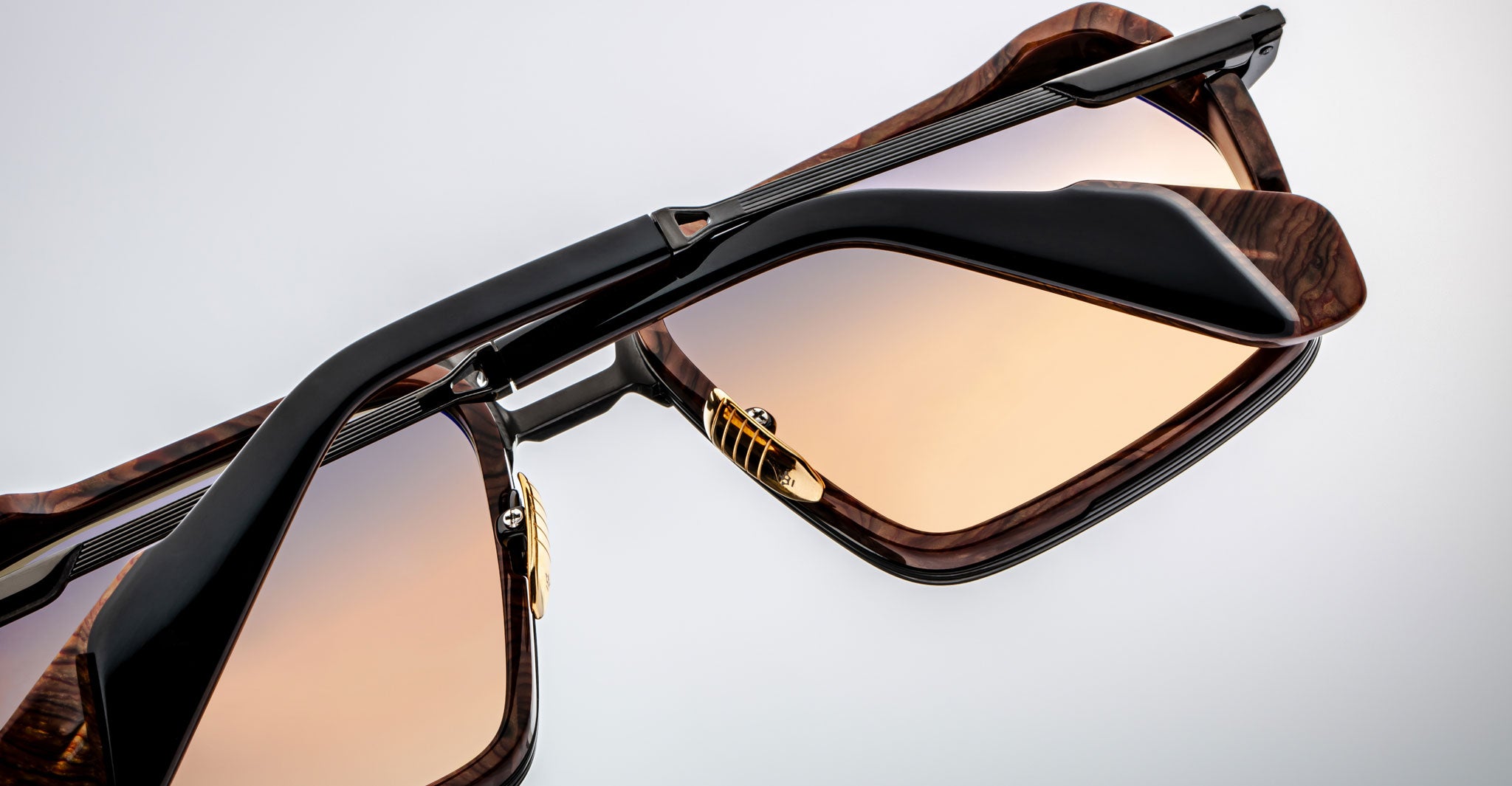 Close-up of Jacques Marie Mage GT-R sunglasses featuring rectangular gradient brown lenses, tortoiseshell frames, black arms, and gold lens accents displayed against a plain light background.