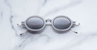 Jacques Marie Mage Balthazar round gray-framed polarized sunglasses with dark lenses, front view.