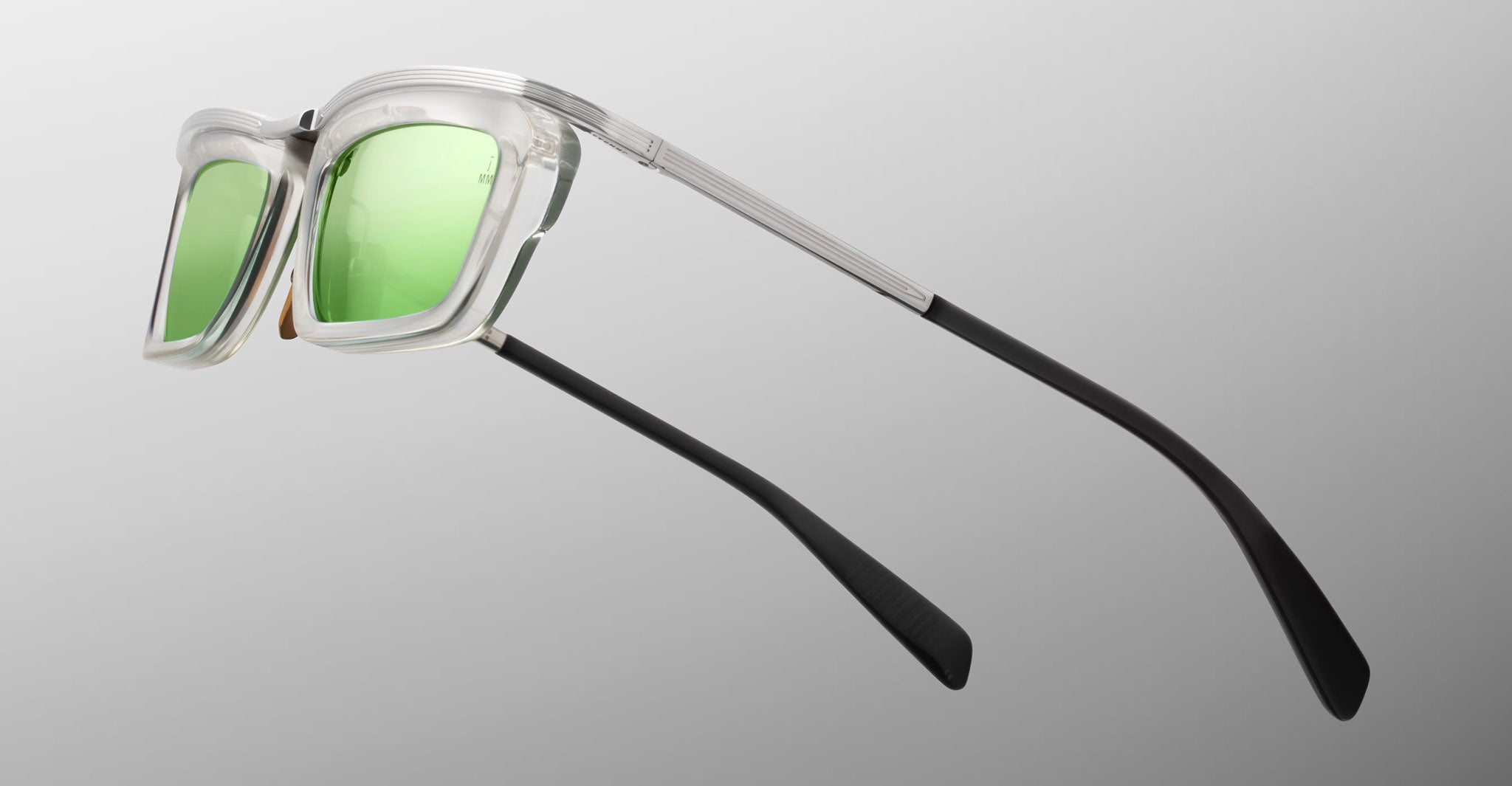 Jacques Marie Mage Gaspard sunglasses with clear frames, green lenses, and black arms shown from the front view.