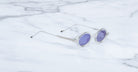 Jacques Marie Mage Balthazar sunglasses with clear round frames and purple lenses, viewed from above.