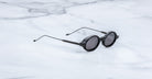 Jacques Marie Mage Balthazar black round sunglasses with thin arms, shown from side angle.