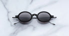 Jacques Marie Mage Balthazar black polarized sunglasses with dark lenses, top view.