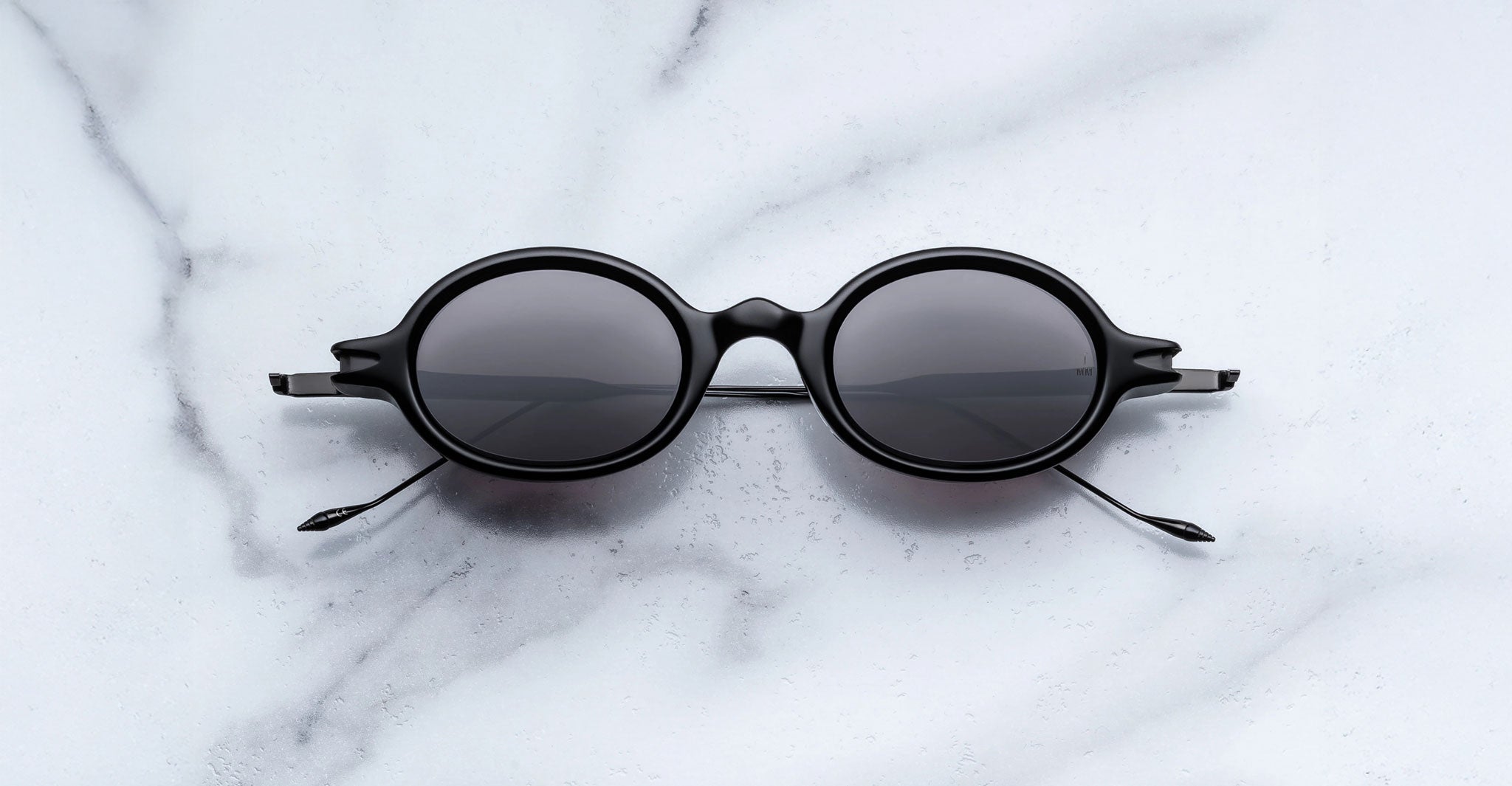 Jacques Marie Mage Balthazar black polarized sunglasses with dark lenses, top view.