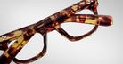 Close-up of two pairs of Jacques Marie Mage Godard tortoiseshell eyeglasses stacked together on a plain white background.