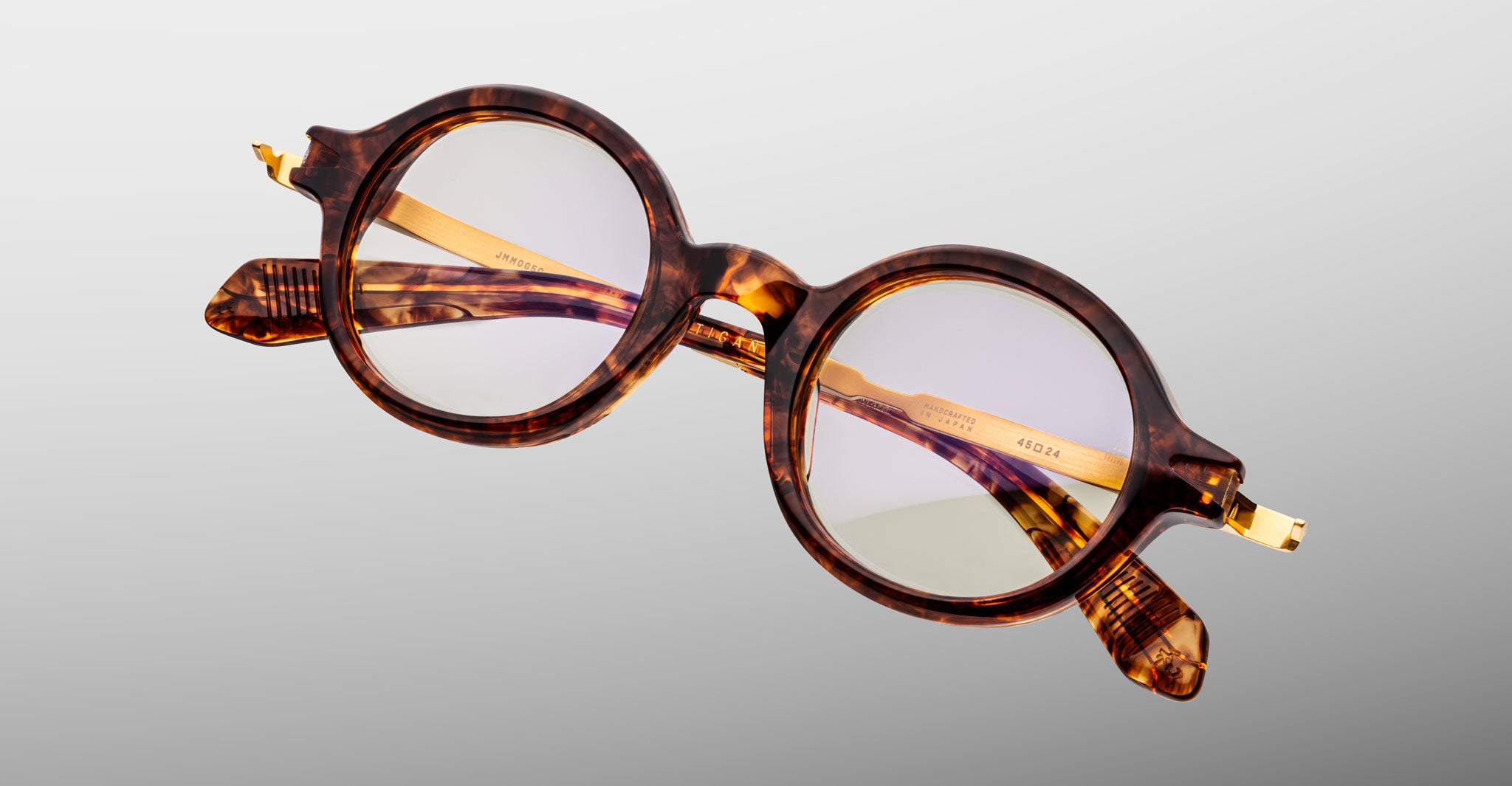 Jacques Marie Mage Hartigan in Argyle, round tortoiseshell acetate eyeglasses shown from a close angled front view, featuring a keyhole bridge, exposed metal core temples, and subtle purple anti-reflective lens coating.
