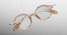 Jacques Marie Mage Hartigan in Sand, round translucent beige acetate eyeglasses shown from an angled top view of the back, highlighting engraved metal core temples, keyhole bridge, and sculpted temple tips with clear demo lenses.