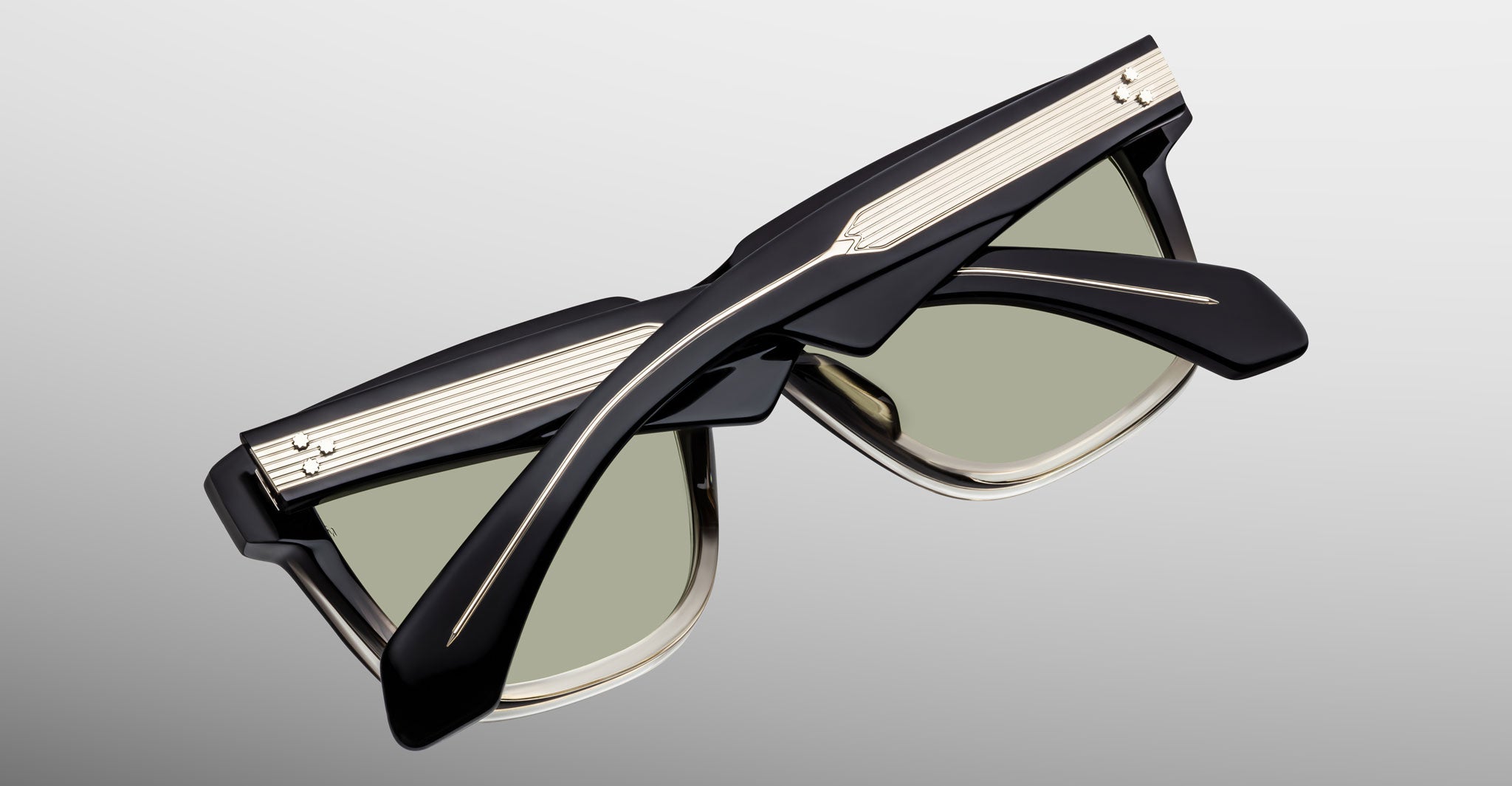 Jacques Marie Mage Hyannis in Black Fade sunglasses in black and taupe with green lenses, folded; modern design shown from a top-down back angle.