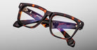 The Jacques Marie Mage Hyannis rectangular eyeglass frames, featuring brown tortoiseshell acetate and clear lenses, are displayed against a plain light background.