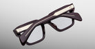 Jacques Marie Mage Ichikawa rectangular eyeglasses with dark thick frames and gold accents, viewed from the front.