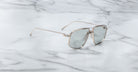 The Jacques Marie Mage Jagger oversized aviator sunglasses feature reflective lenses and a silver beta titanium frame, displayed on a white marble surface.