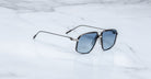 The Jacques Marie Mage Jagger oversized aviator sunglasses with blue tinted lenses from Jacques Marie Mage rest elegantly on a white marble surface.