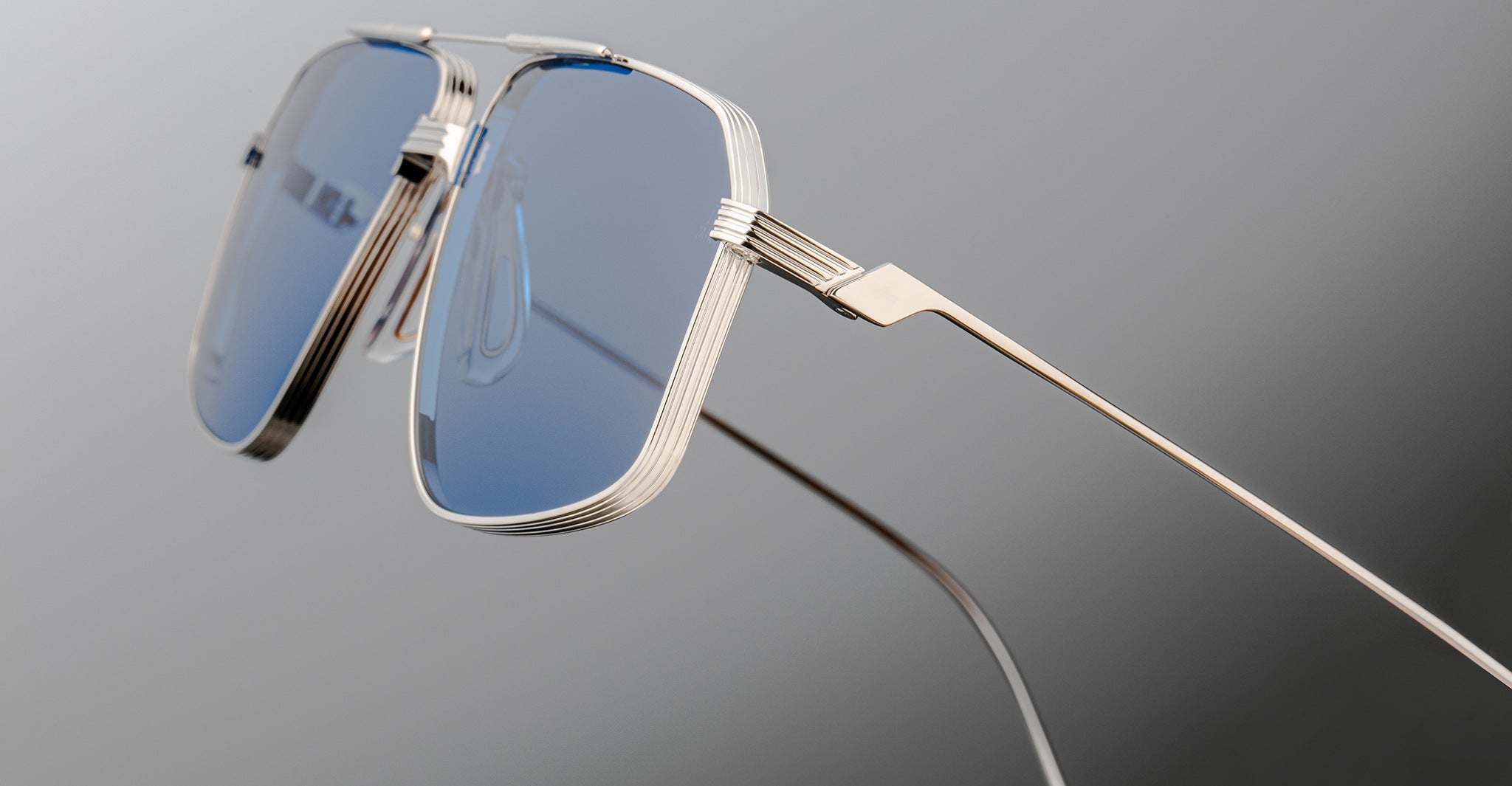 Close-up of Jacques Marie Mage Jagger oversized aviator sunglasses by Jacques Marie Mage, featuring blue-tinted lenses and sleek beta titanium frames against a neutral background.
