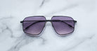 Jacques Marie Mage Jagger oversized aviator sunglasses by Jacques Marie Mage, with black frames and purple-tinted lenses, displayed on a white marble surface.