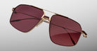 The Jacques Marie Mage Jagger sunglasses by Jacques Marie Mage feature a gold frame and large square burgundy-tinted lenses, showcased against a plain gray background.