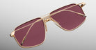 Jacques Marie Mage Jagger sunglasses by Jacques Marie Mage feature a beta titanium frame, gold rims, oversized rectangular rose-tinted lenses, and are shown on a light gray background.