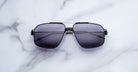 Jacques Marie Mage Jagger oversized aviator sunglasses with dark tinted lenses by Jacques Marie Mage, displayed on a white marble surface.