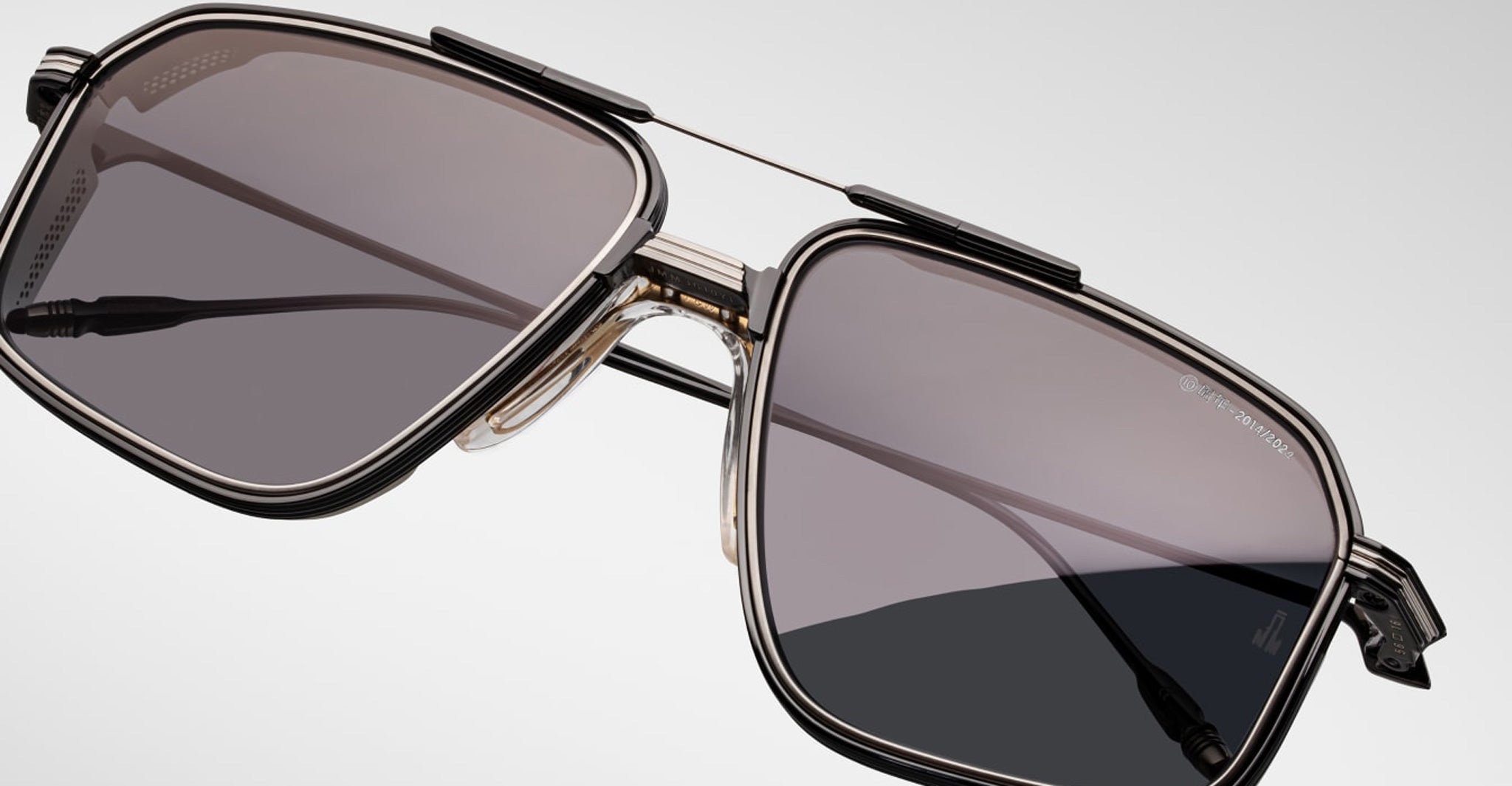 Close-up of Jacques Marie Mage Jagger sunglasses by Jacques Marie Mage, showcasing oversized square aviator frames in beta titanium with dark tinted lenses against a plain light background.