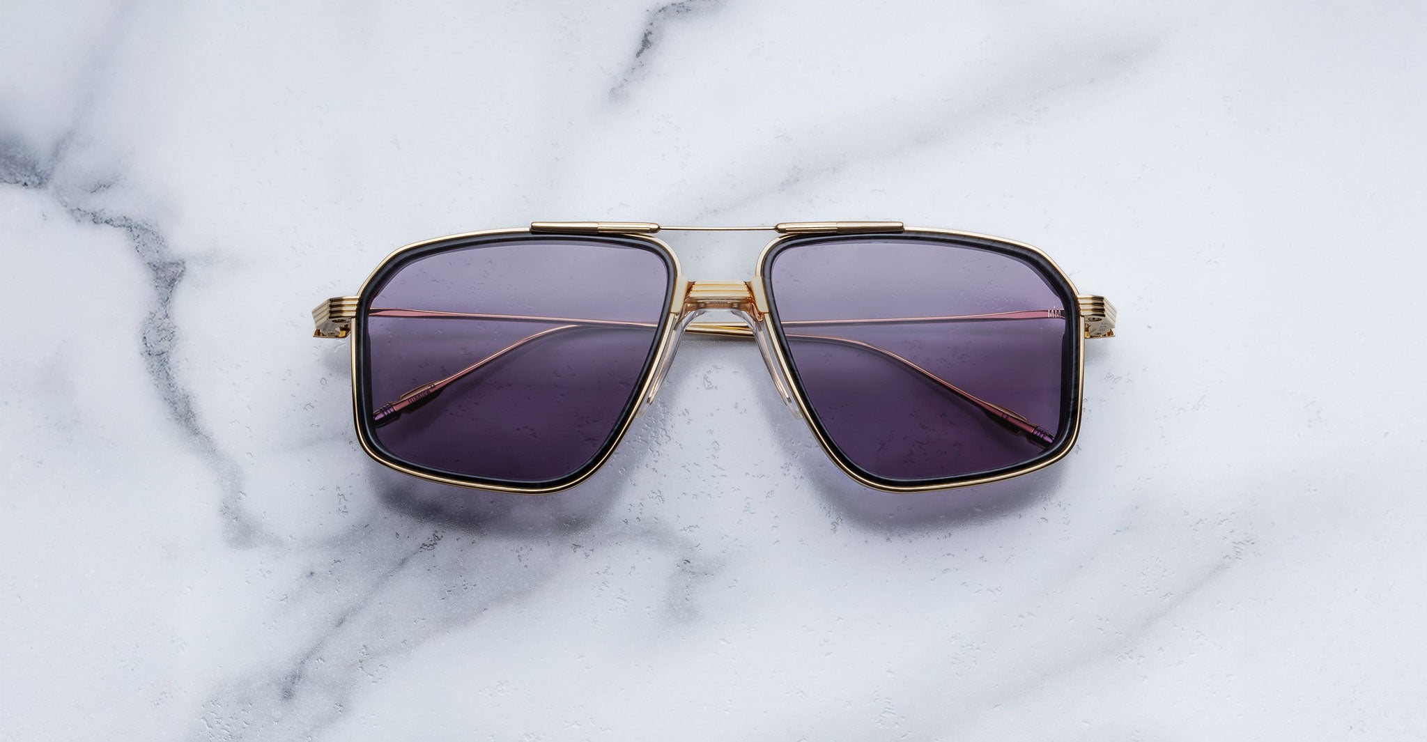 Jacques Marie Mage Jagger aviator sunglasses with gold frames and dark lenses, top view.