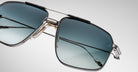 Close-up of Jacques Marie Mage Jagger sunglasses, featuring an oversized aviator design with blue gradient lenses, a silver beta titanium frame, and transparent nose pads against a plain light background.