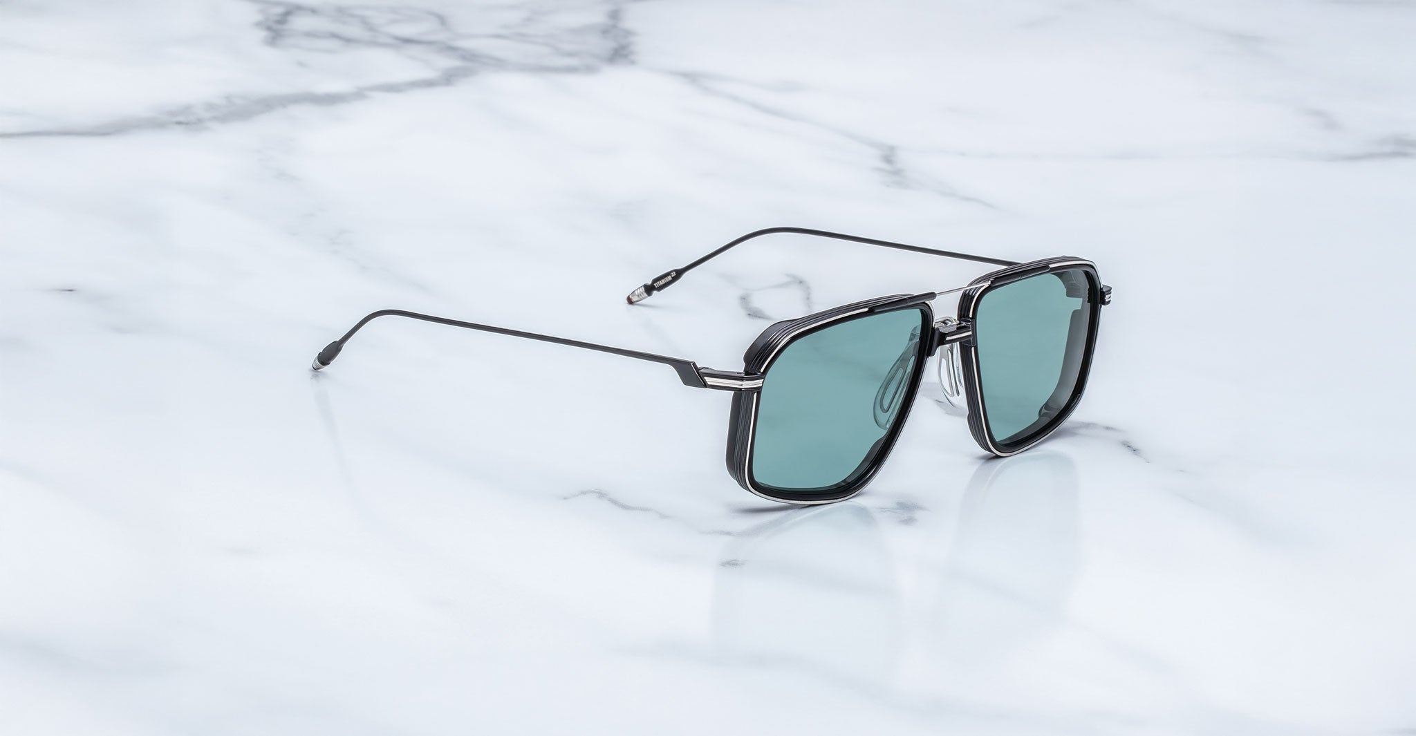 Jacques Marie Mage Jagger sunglasses with black rims and green lenses, shown from above.