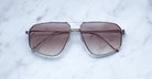 A pair of Jacques Marie Mage Jagger oversized aviator sunglasses with brown gradient lenses and thin beta titanium frames from Jacques Marie Mage, displayed on a white marble surface.