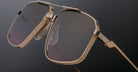 Close-up of Jacques Marie Mage Jagger aviator sunglasses by Jacques Marie Mage, featuring a gold geometric beta titanium frame, tinted lenses, and prominent nose pads, inspired by the iconic Jagger style against a dark background.