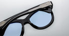 Close-up of Jacques Marie Mage Jennie sunglasses in black with light blue polarized lenses and silver detailing on the temples.