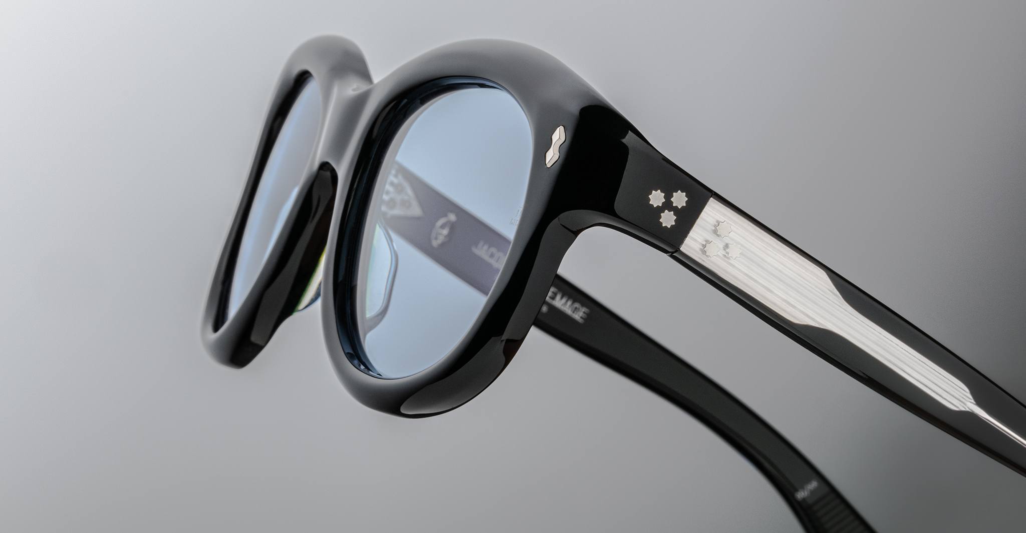 Jacques Marie Mage Jennie eyeglasses, black and white frame, blue-tinted lenses, close-up side angle.
